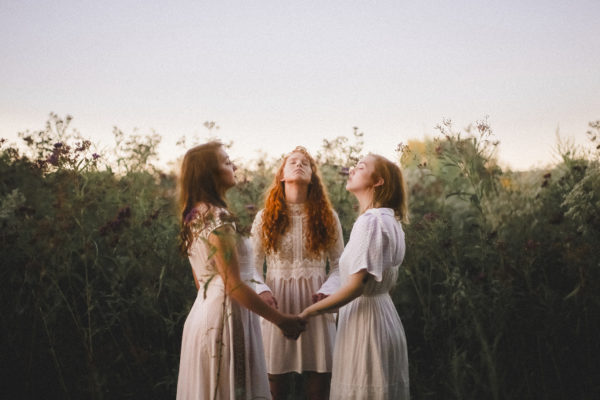 3 women praying together in a field