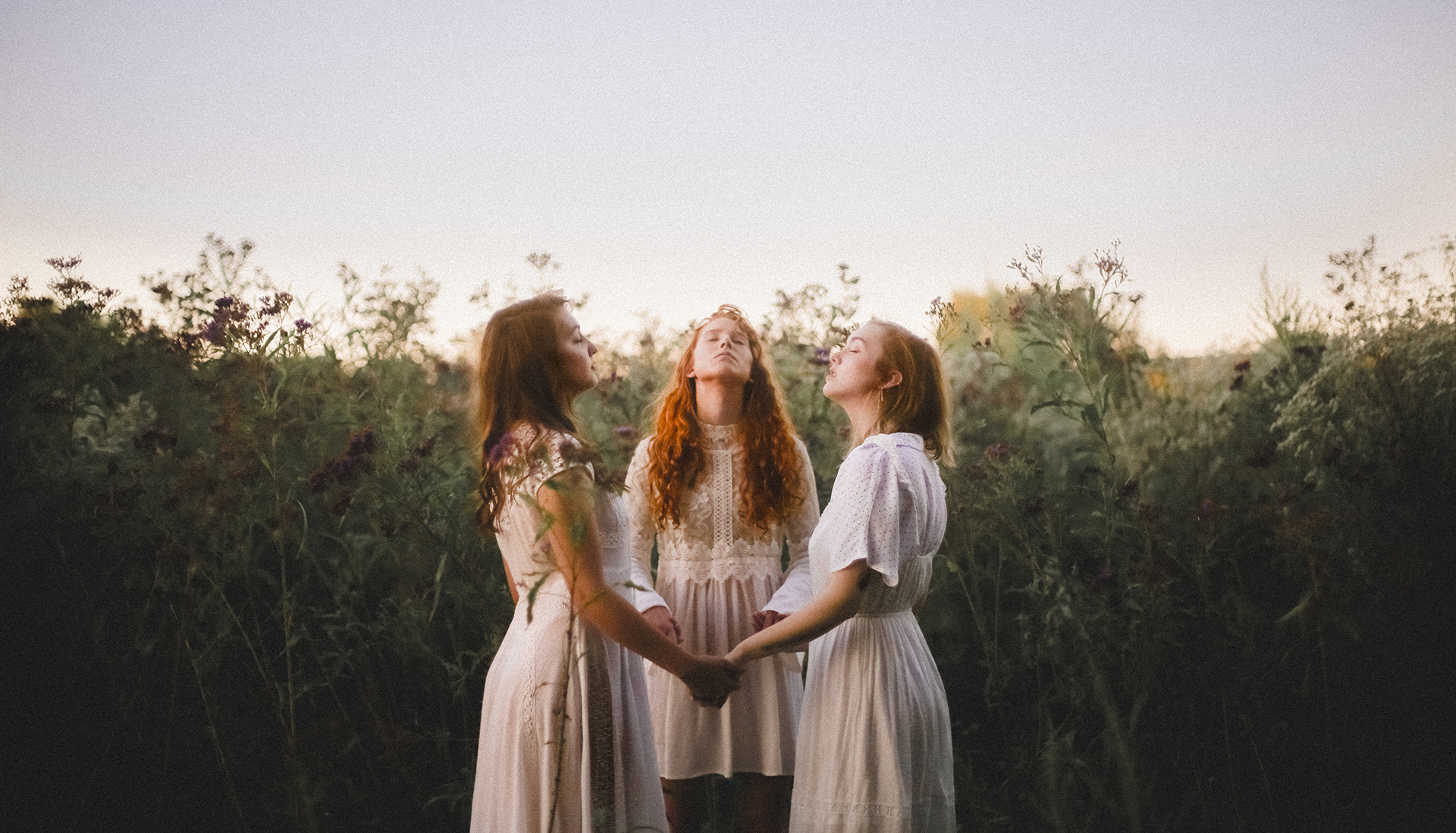 3 women praying together in a field